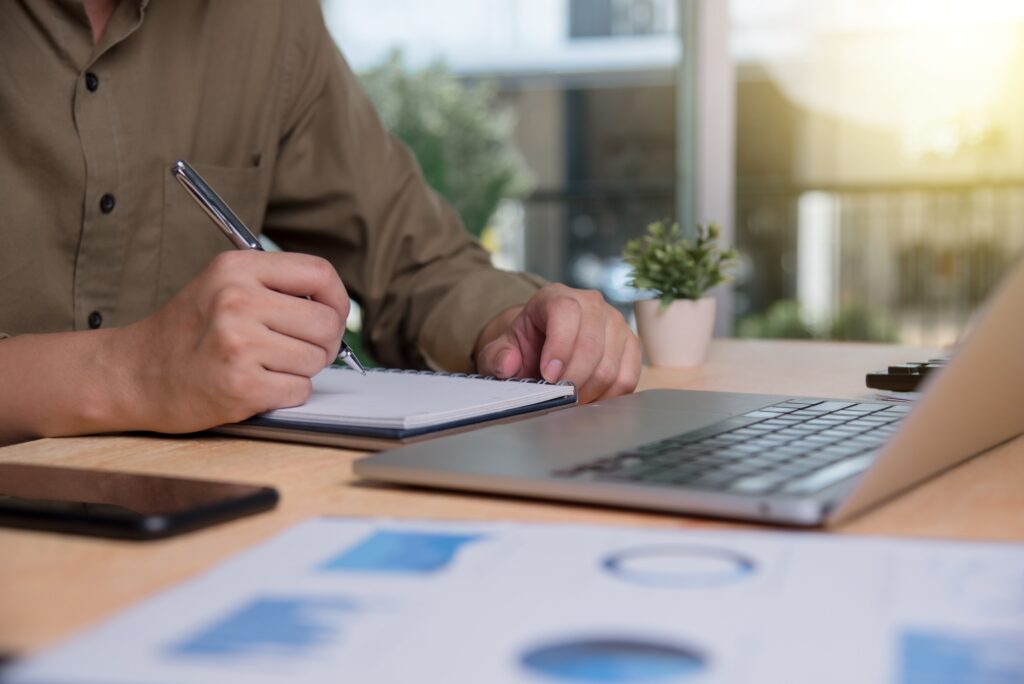 Businessperson writing notes while planning in an office setting, emphasizing strategic thinking and