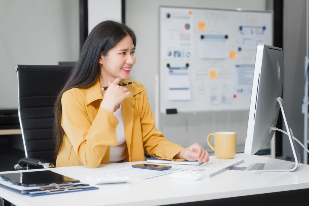 Young Asian woman at desk, managing HR, legal consulting, and compliance amidst files